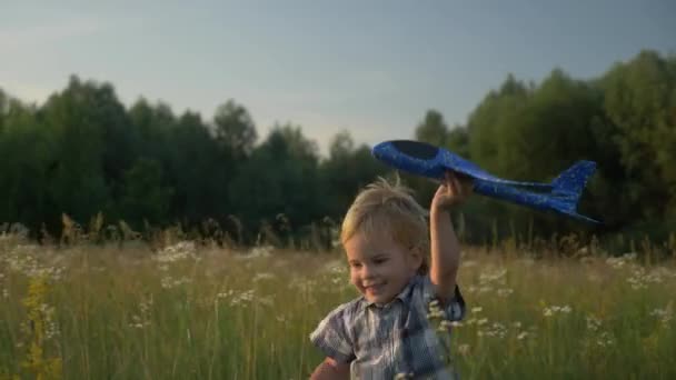 芝生広場の向こうでおもちゃの飛行機で遊んで走っている小さな男の子 田舎の夕日の風景 2倍スローモーション ハーフスピード60 Fps — ストック動画