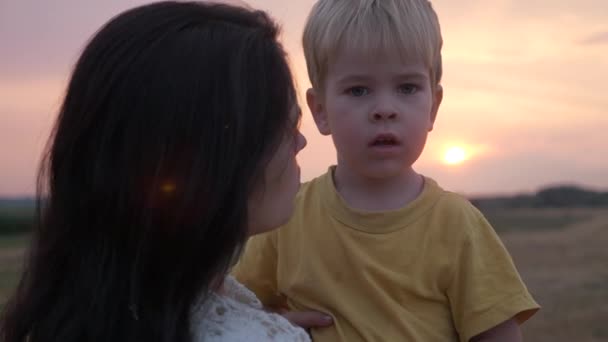 快乐的母亲和儿子在日落前的田野里 表达爱与幸福的快乐积极的情感 — 图库视频影像
