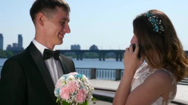 Damat, Gelin Akıllı Telefonla Konuşurken Bekliyor. Şehir manzarası arka planı. 2x Yavaş çekim - 0.5 Hız 60 FPS