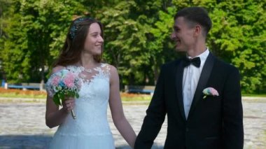 Gelin ve Damat Park 'ta yürüyüp birbirlerine bakıyorlar. Şehir Sahnesi. Yavaş çekim - 0.5 Hız 60 FPS 