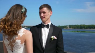 Gelin ve damat nehir kenarında yürüyor. Düğün günü. Şehir manzarası Şehir Sahnesi. 2x Yavaş çekim - 0.5 Hız 4K 60 FPS