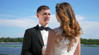 Gelin ve damat nehir kenarında yürüyor. Düğün günü. Şehir manzarası Şehir Sahnesi. 2x Yavaş çekim - 0.5 Hız 4K 60 FPS
