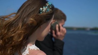 Gelin ve Çiçek Buketi, Damat Akıllı Telefonda Sohbet Ederken Bekliyor. Şehir manzarası arka planı. 2x Yavaş çekim - 0.5 Hız 60 FPS 4K