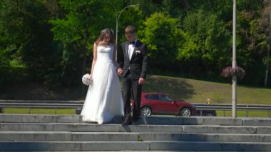 Gelin ve Damat Park 'ta yürüyüp birbirlerine bakıyorlar. Şehir Sahnesi. Yavaş çekim - 0.5 Hız 60 FPS 