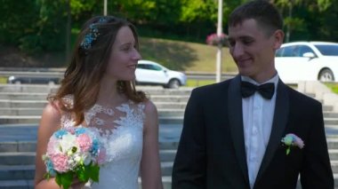 Gelin ve Damat Park 'ta yürüyüp birbirlerine bakıyorlar. Şehir Sahnesi. Yavaş çekim - 0.5 Hız 60 FPS 