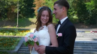 Gelin ve Damat Park 'ta yürüyüp birbirlerine bakıyorlar. Şehir Sahnesi. Yavaş çekim - 0.5 Hız 60 FPS 