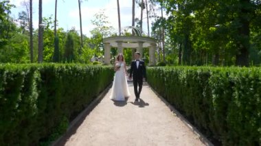 Gelin ve Damat Park 'ta yürüyüp birbirlerine bakıyorlar. Şehir Sahnesi. Yavaş çekim - 0.5 Hız 60 FPS 