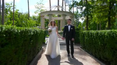Gelin ve Damat Park 'ta yürüyüp birbirlerine bakıyorlar. Şehir Sahnesi. Yavaş çekim - 0.5 Hız 60 FPS 