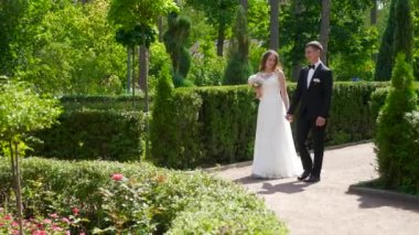 Gelin ve Damat Park 'ta yürüyüp birbirlerine bakıyorlar. Şehir Sahnesi. Yavaş çekim - 0.5 Hız 60 FPS 