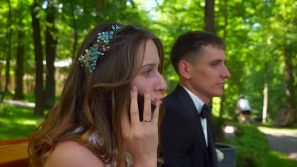 Bride Chatting Smartphone While Groom Waiting Couple Siting Bench Park — Stock Video