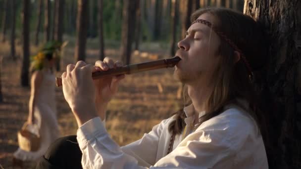 Homem Close Com Cabelos Longos Toca Flauta Sob Pinheiros Background — Vídeo de Stock