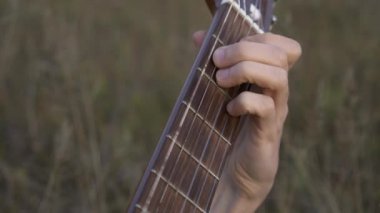 Yakın plan Müzisyen Saha Arasında Otururken Gitar Üzerinde Çalıyor. 4K HDR