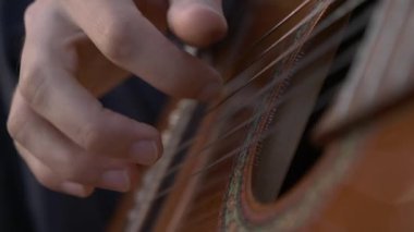 Yakın plan Müzisyen Saha Arasında Otururken Gitar Üzerinde Çalıyor. 4K HDR