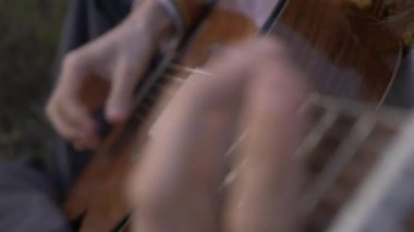 Yakın plan Müzisyen Saha Arasında Otururken Gitar Üzerinde Çalıyor. 4K HDR