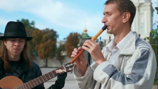 2人のストリート ミュージシャンがシティ スクエアでギターとフルートを演奏する 秋の朝 — ストック動画