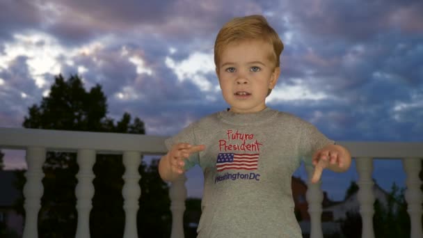 小さな男の子が手を振っている 子供はサイン未来の社長とアメリカ国旗とTシャツに身を包んだ スローモーション60 Fps — ストック動画