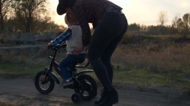 Anne, Oğula Kırsal Toprak Yolu 'nda ilk kez bisiklete binmeyi öğretiyor. Yavaş çekim