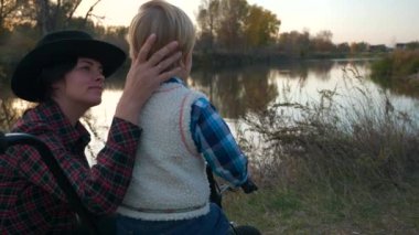 Anne ve Oğlu Nehir kenarında Bisiklet Yürüyüşü. Çocuk, Dünya Annesinin Doğa Çevresi Hakkında Söyledikleri 'ni keşfeder. Kırsal kesimde günbatımı. Yavaş çekim