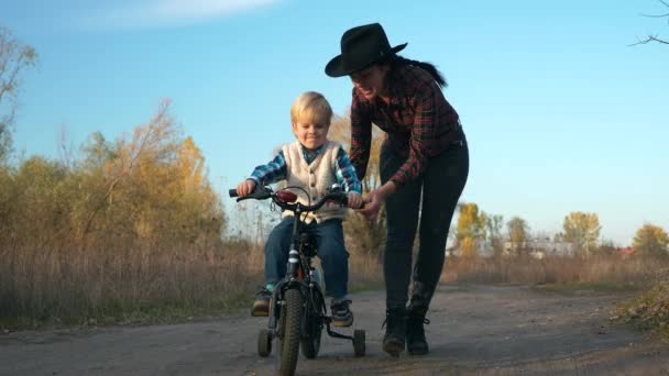 母亲第一次教儿子骑自行车在乡间土路上 慢动作 — 图库视频影像