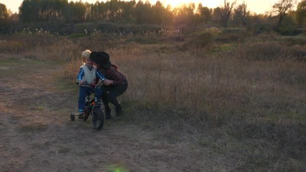 Älskar Moder Kyssar Barn Medan Lär Honom Att Cykla Kvällssolnedgång — Stockvideo