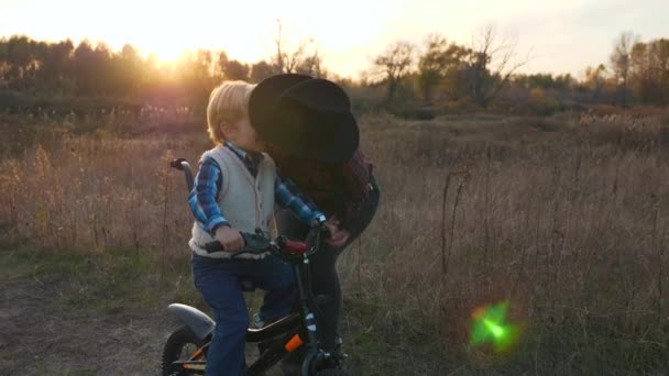 Kochająca Matka Całuje Dziecko Ucząc Jeździć Rowerze Wieczorna Scena Zachodzie — Wideo stockowe