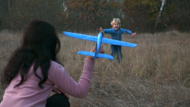 息子と母はおもちゃの飛行機を起動屋外で再生します ハッピー ボーイ チャイルドが飛行機に乗る 秋の野外林 2Xスローモーション60 Fps — ストック動画