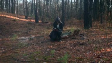 Siyah pelerinli keşiş el ele tutuşarak İncil 'i kaldırdı. Misty Wood 'da güneş ışığı. Sonbahar Sabahı. 2x Yavaş çekim 60 fps