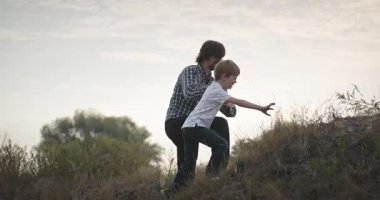 İnsan ve Çocuk Tarladaki Tepeye Tırmanır. Baba ve Çocuk Doğa 4K 10-bit 'te Birlikte Zaman Geçiriyorlar