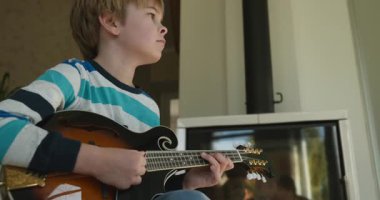 Beyaz çocuk evde Mandolin oynuyor. Avrupalı Çocuk Müzik Çalışması 4K 10-bit