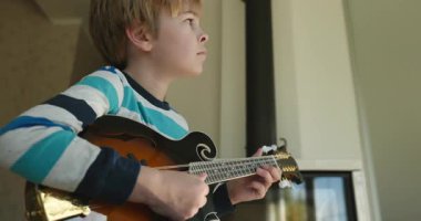 Beyaz çocuk evde Mandolin oynuyor. Avrupalı Çocuk Müzik Çalışması 4K 10-bit