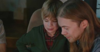 Amcası ve babası olan bir çocuk heyecanlı bir kitap okuyor. 4K 10-bit eğleniyor.