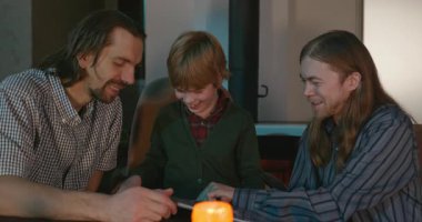 Amcası ve babası olan bir çocuk heyecanlı bir kitap okuyor. 4K 10-bit eğleniyor.