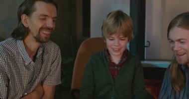 Amcası ve babası olan bir çocuk heyecanlı bir kitap okuyor. 4K 10-bit eğleniyor.