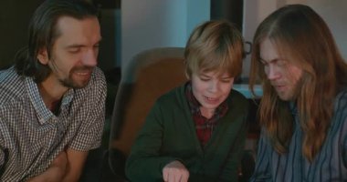 Amcası ve babası olan bir çocuk heyecanlı bir kitap okuyor. 4K 10-bit eğleniyor.