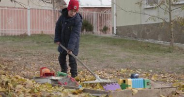 Boy Rakes Arka Bahçede Yapraklar. Soğuk Sonbahar Havası Ağır çekim 4K 10-bit 