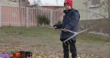 Boy Rakes Arka Bahçede Yapraklar. Soğuk Sonbahar Havası Ağır çekim 4K 10-bit 
