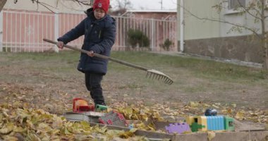 Boy Rakes Arka Bahçede Yapraklar. Soğuk Sonbahar Havası Ağır çekim 4K 10-bit 