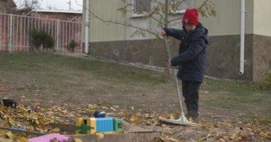 Boy Rakes Arka Bahçede Yapraklar. Soğuk Sonbahar Havası Ağır çekim 4K 10-bit 