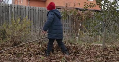 Boy Rakes Arka Bahçede Yapraklar. Soğuk Sonbahar Havası Ağır çekim 4K 10-bit 