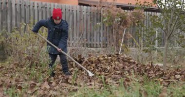 Boy Rakes Arka Bahçede Yapraklar. Soğuk Sonbahar Havası Ağır çekim 4K 10-bit 