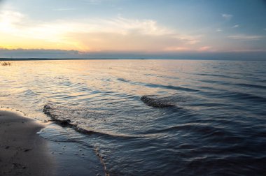 Kumlu sahilde günbatımı dalgalar deniz. Ladoga Gölü.