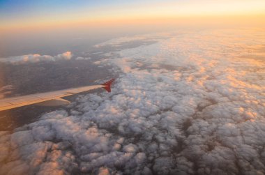 Bulutların üzerinde güneş doğarken uçan uçak. Hava penceresi görünümü.