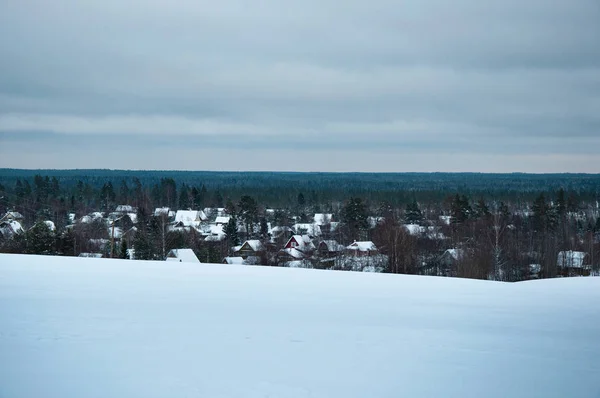 丘や森林に覆われた夜の雪の中で村の風景 — ストック写真
