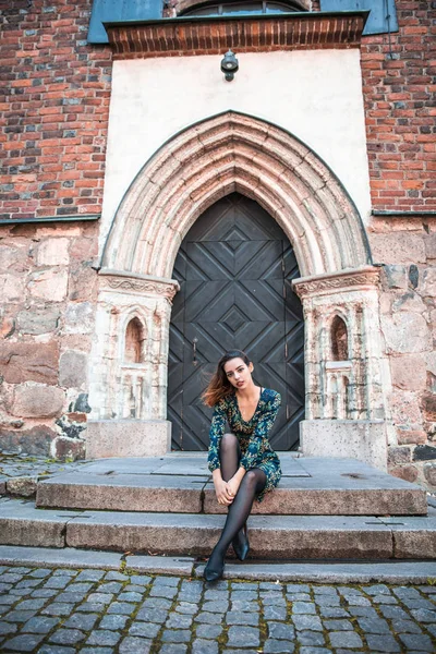 Güzel, sıska Arnavut kız poz veriyor ve turuncu mavi süs elbisesini gösteriyor