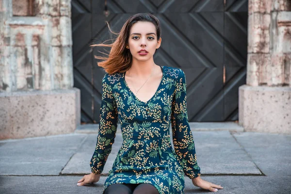 Güzel, sıska Arnavut kız poz veriyor ve turuncu mavi süs elbisesini gösteriyor