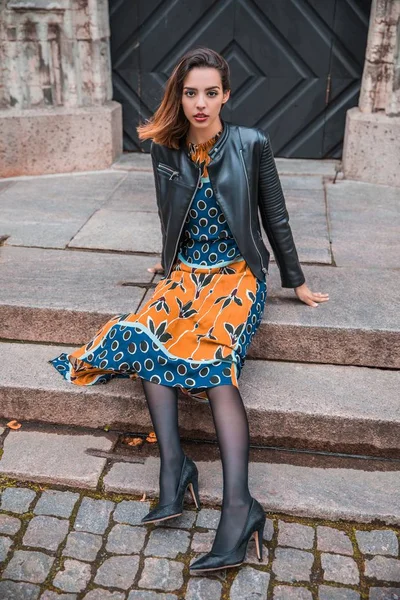 Güzel, sıska Arnavut kız poz veriyor ve turuncu mavi süs elbisesini gösteriyor