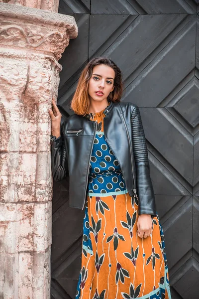 Güzel, sıska Arnavut kız poz veriyor ve turuncu mavi süs elbisesini gösteriyor