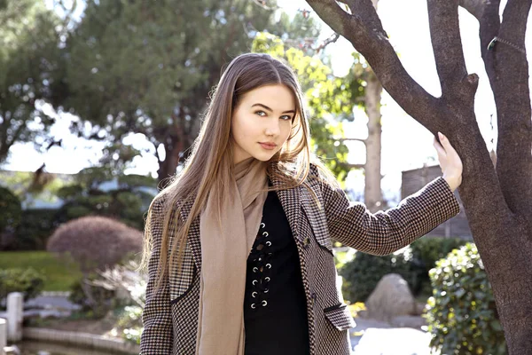 Baharda bahçede poz veren uzun saçlı genç kız.