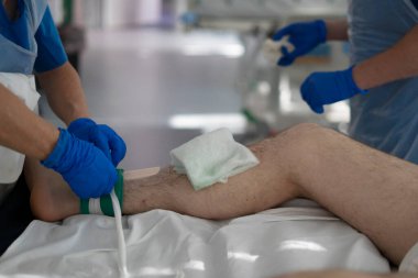 Medical professional providing post-operative care, bandaging a patient's leg in a sterile hospital environment