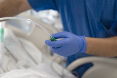 Medical staff member wearing blue gloves managing patient care equipment